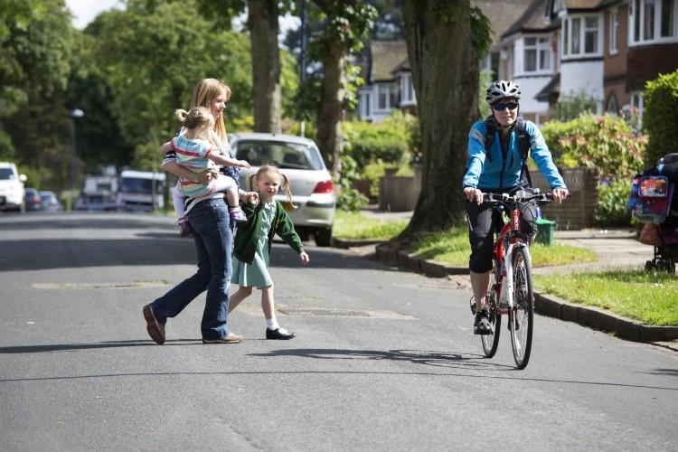 Family walking and cyclist on local street
